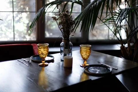 Beautiful table setting with glasses of wine and rose in dark room. Romantic Stock Photos