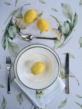 Beautiful table setting - printed tablecloth, plate, yellow lemons Stock Photos
