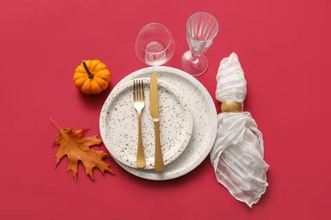 Beautiful table setting with pumpkin and autumn leaf on red background Stock Photos