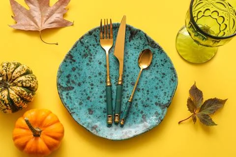 Beautiful table setting with pumpkins and autumn leaves on yellow background Stock Photos