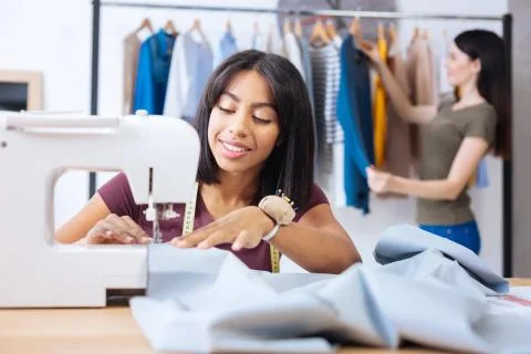 Beautiful tailor looking attentive while sewing clothes at work Stock Photos