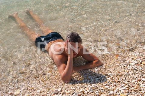 Beautiful tanned young fellow in sea water Stock Photos