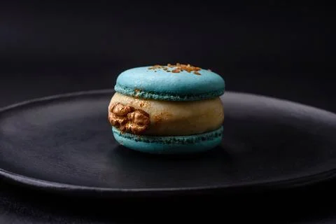 Beautiful tasty macaron with filling and fruit flavor on a black plate on a d Stock Photos