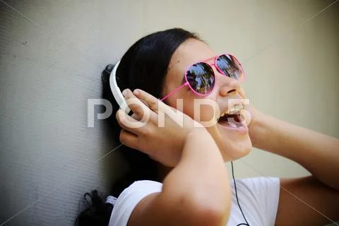 Beautiful teenage girl listening to music on headphones and enjoying Stock Photos