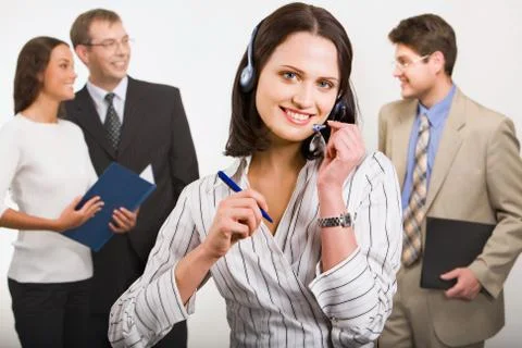 Beautiful telephone operator is holding headset and pen on the background of  he Stock Photos