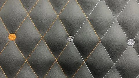 Beautiful thread stitching and embroidery orange and white on the black lea.. Stock Photos