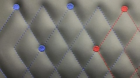 Beautiful thread stitching and embroidery blue and red on the black leather. Stock Photos