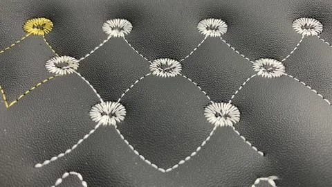 Beautiful thread stitching and embroidery on the black leather. Stock Photos