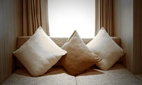 Beautiful three pillows on sofa interior decoration in living room with curtains Stock Photos