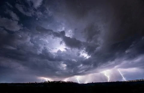Beautiful thunderstorm with clouds and lightning over the night city Stock Photos