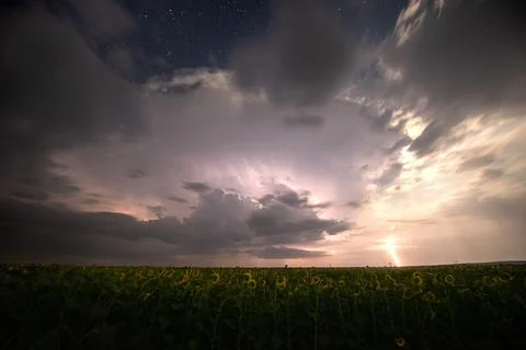 Beautiful thunderstorm with clouds, lightning and moon over a field Stock Photos