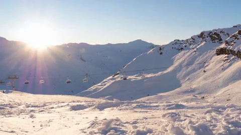 Beautiful timelapse of the sun setting behind snowy mountains with ski lift Video stock 127054402