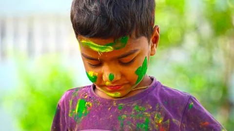 Beautiful toddler kid posing with exploding Green and yellow powder on face.  Stock Photos