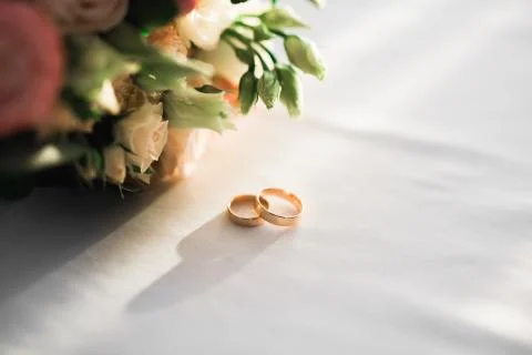 Beautiful toned picture with wedding rings against the background of a bouquet Stock Photos