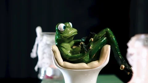 Beautiful toy in the form of a frog sitting in a chair. Close-up in motion. Stock Footage 123378085