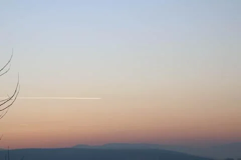 A beautiful trace of plane on a sky in gradient during sunset. Stock Photos