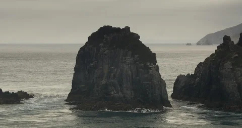 Beautiful Tracking Shot of Rock Formations and Mountains in New Zealand Ocean Видео 87104967