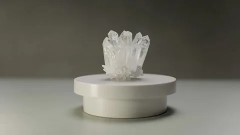 A beautiful translucent crystal is spinning on a white pedestal. Stock Footage 305622879