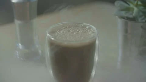 Beautiful transparent cup with coffee and frothy top on the table Stock Footage 100900414