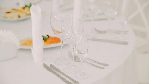 Beautiful transparent glasses stand on a table with a white tablecloth Stock Footage 121157922