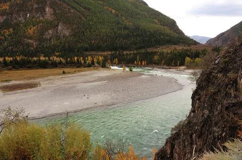 A beautiful turquoise river flows through the autumn valley at the foot of a Stock Photos
