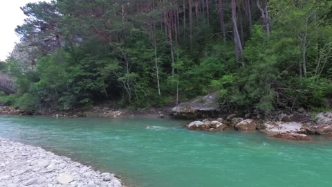 A beautiful turquoise river flows under a bridge in the mountainous regions of P Stock Footage 94371560