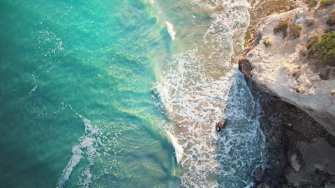 Beautiful turquoise waves slowly rolling onto the rocky shore in summer. Stock Footage 161328338