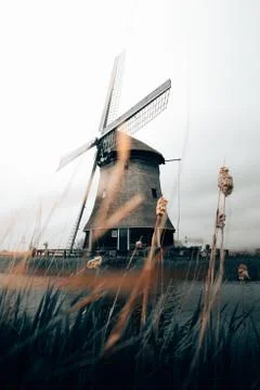 A beautiful vertical shot of a spinning windmill with clear white sky in Rust Stock Photos
