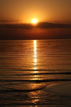 Beautiful vertical sunset landscape featuring a glowing sun path on the sea Stock Photos
