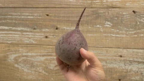 A Beautiful Vibrant Beetroot Being Held in Hand Against a Detailed Rustic Видео 280590620