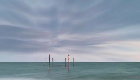 Beautiful vibrant conceptual image of posts in sea standing sentinel against Stock Photos