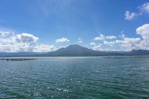 Beautiful view of active volcano Mount Batur with Lake Batur and blue sky in  Stock Photos