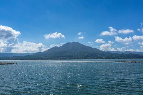 Beautiful view of active volcano Mount Batur with Lake Batur and blue sky in  Stock Photos