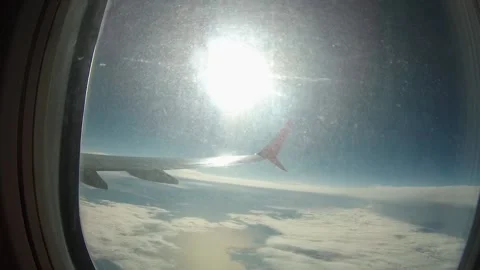 Beautiful view from the airplane window window with blue sky, bright suns and wh Vidéo 156604909