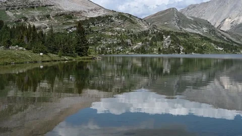 Beautiful view of a calm mountain lake that is reflecting the mountains and sky  Stock Footage 279097232