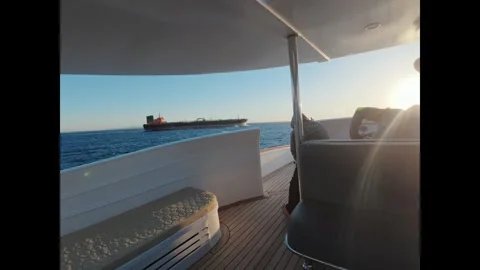 Beautiful view of a cargo ship sailing on the sea during a golden sunset from a Stock-Footage 335817900