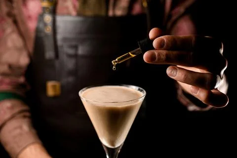 Beautiful view of dropper with falling drop in martini glass with cocktail Stock Photos