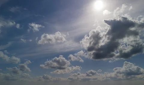 A beautiful view of fluffy clouds in a bright blue sky with the sun shining. Stock Photos