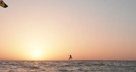 Beautiful view of a kite surfer riding a kite surf against sunset. Watersport Stock Footage 273382247