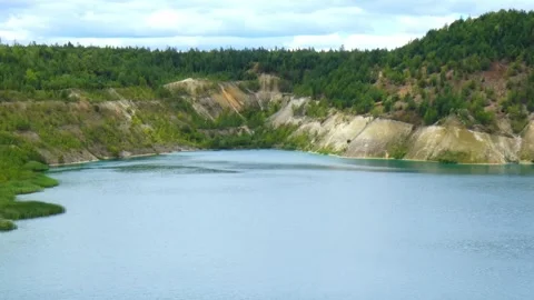 Beautiful view of a lake surrounded by trees and rocky cliffs in a remote area Видео 340448111