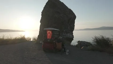 Beautiful view of a man relaxing by a large rock by the sea Stock Footage 311113839