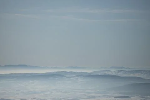 Beautiful view of the mountain range partially covered by fog and snow with c Stock Photos
