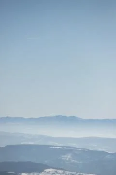 Beautiful view of the mountain range partially covered by fog and snow with c Stock Photos