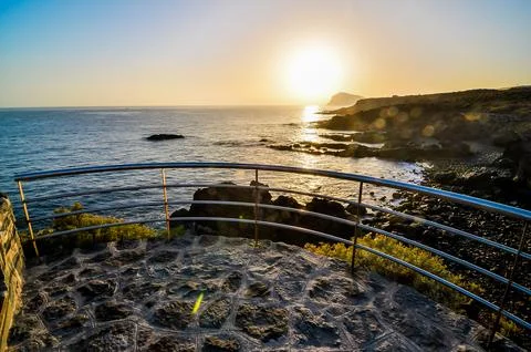 A beautiful view of the ocean with a sun setting in the background Stock Photos
