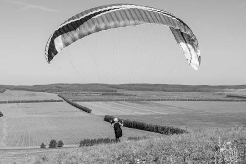 Beautiful view of a pilot with paraplan going to start flying over the fields in 写真素材