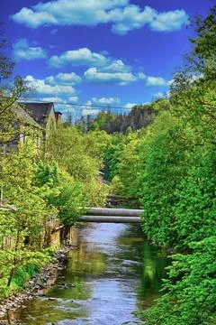 Beautiful view of a river surrounded by trees and buildings under a clear b.. Stock Photos