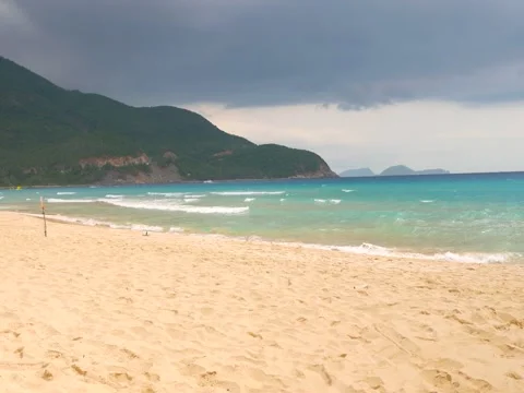 Beautiful view of sandy beach and waving blue sea water with stormy sky in the 스톡 동영상 62620562