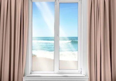 Beautiful view of sandy beach washed by sea on sunny day through window Stock Photos
