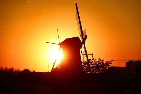 Beautiful view of a silhouette of a windmill in the field at golden hour Stock Illustration