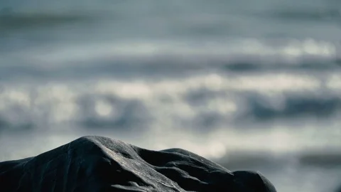 Beautiful view of slow motion out of focus waves behind smooth rocks on beach v2 Stock Footage 119533164